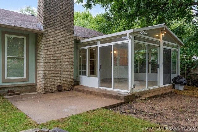 349 S 185th E Ave, Tulsa, OK 74108 - rear view of property featuring a sunroom, a chimney, a shingled roof, a patio area, and brick siding