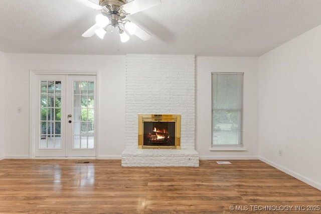 349 S 185th E Ave, Tulsa, OK 74108 - unfurnished living room featuring wood finished floors, a textured ceiling, ceiling fan, baseboards, and a fireplace