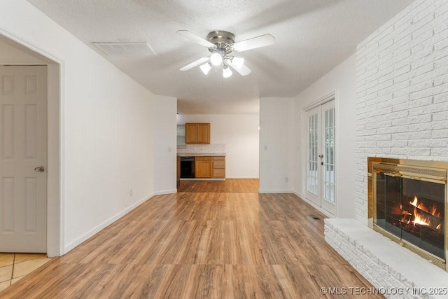 349 S 185th E Ave, Tulsa, OK 74108 - unfurnished living room featuring ceiling fan, light wood finished floors, a brick fireplace, a textured ceiling, and baseboards