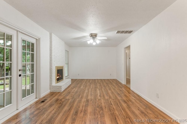 349 S 185th E Ave, Tulsa, OK 74108 - unfurnished living room with wood finished floors, ceiling fan, a brick fireplace, a textured ceiling, and baseboards