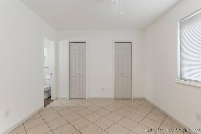 349 S 185th E Ave, Tulsa, OK 74108 - unfurnished bedroom with two closets, light tile patterned floors, baseboards, and connected bathroom