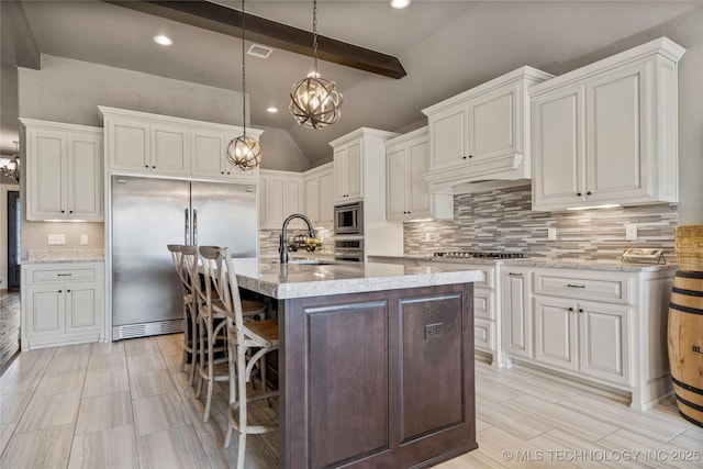 12934 S 2nd St, Jenks, OK 74037 - kitchen with built in appliances, a sink, tasteful backsplash, light stone counters, and a kitchen breakfast bar