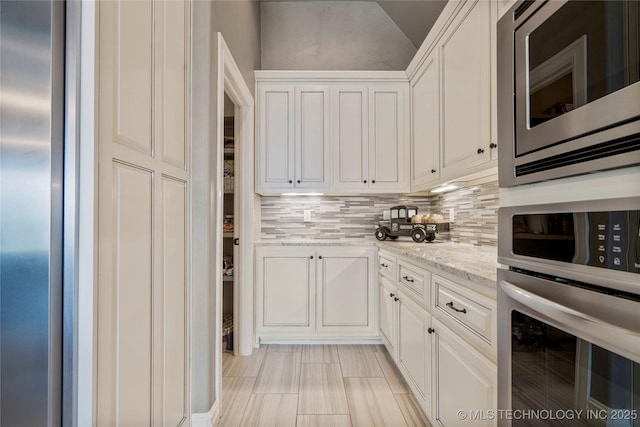 12934 S 2nd St, Jenks, OK 74037 - kitchen featuring stainless steel appliances, decorative backsplash, light stone countertops, white cabinetry, and lofted ceiling
