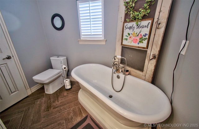 2430 S 31st St E, Muskogee, OK 74403 - bathroom featuring a soaking tub, toilet, and baseboards
