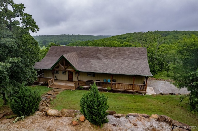 5687 Lake Jackson Rd, Mounds, OK 74047 - rustic home with a wooded view, covered porch, a shingled roof, and a front lawn
