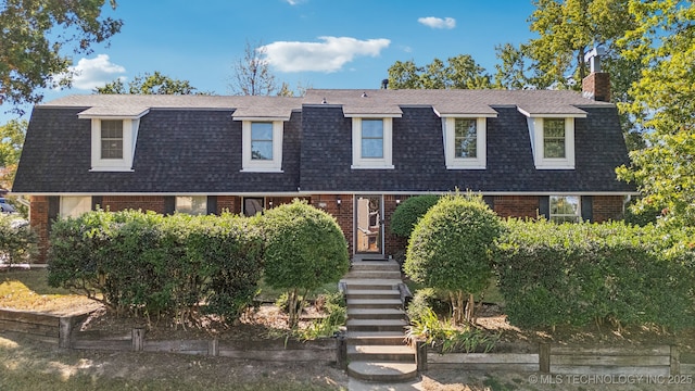 6506 E 99th St, Tulsa, OK 74133 - view of front of property featuring roof with shingles, brick siding, and a chimney