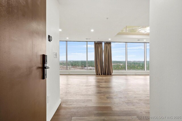 5810 E Skelly Dr Unit 303, Tulsa, OK 74135 - empty room featuring recessed lighting, wood finished floors, a wall of windows, and baseboards