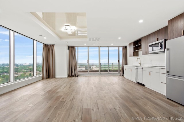 5810 E Skelly Dr Unit 303, Tulsa, OK 74135 - kitchen with appliances with stainless steel finishes, expansive windows, open shelves, light countertops, and light wood-style floors