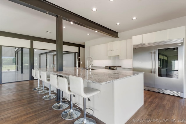 14382 Adams Rd, Mounds, OK 74047 - kitchen with stainless steel built in fridge, beam ceiling, white cabinetry, dark wood finished floors, and a kitchen bar