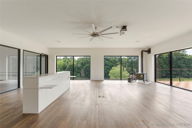 14382 Adams Rd, Mounds, OK 74047 - unfurnished living room with a wood stove, a ceiling fan, and healthy amount of natural light