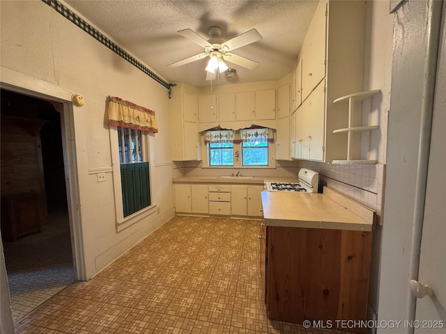 1524 W Maple St W, Durant, OK 74701 - kitchen with white range, open shelves, light countertops, white cabinets, and a textured ceiling
