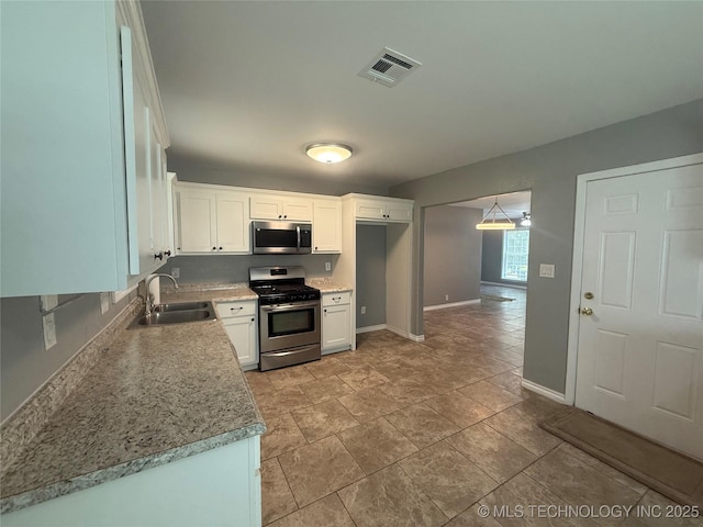 1618 Houston St, Muskogee, OK 74403 - kitchen with appliances with stainless steel finishes, a sink, white cabinets, baseboards, and light countertops