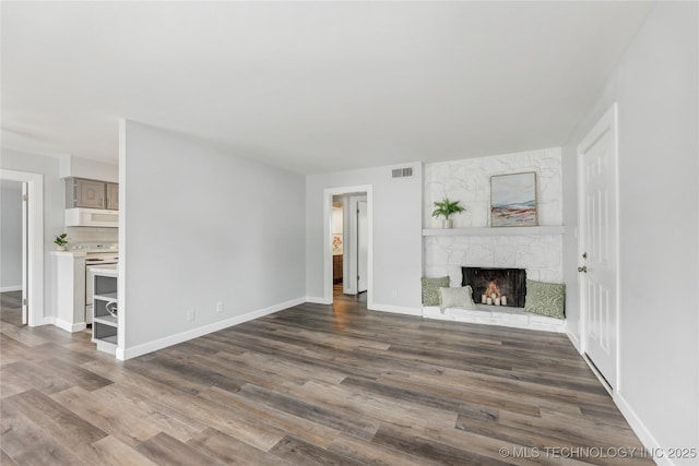 4440 68th St Unit 486, Tulsa, OK 74136 - unfurnished living room featuring a stone fireplace, dark wood-type flooring, and baseboards