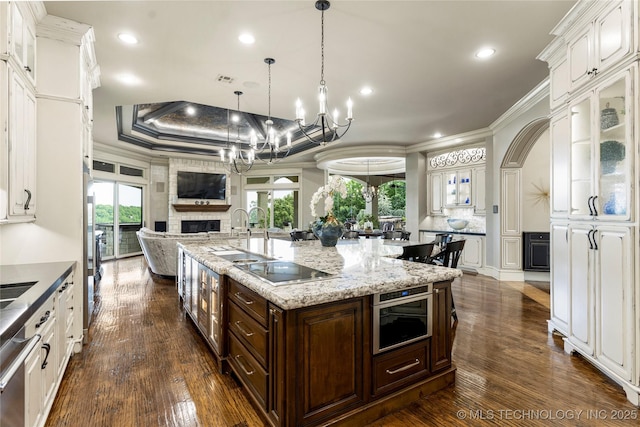 5879 N Eagle Summit Rd, Owasso, OK 74055 - kitchen featuring white cabinetry, a chandelier, ornamental molding, glass insert cabinets, and open floor plan