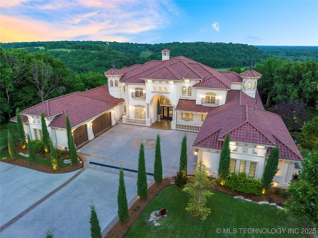 5879 N Eagle Summit Rd, Owasso, OK 74055 - mediterranean / spanish-style house with concrete driveway, an attached garage, a forest view, and stucco siding