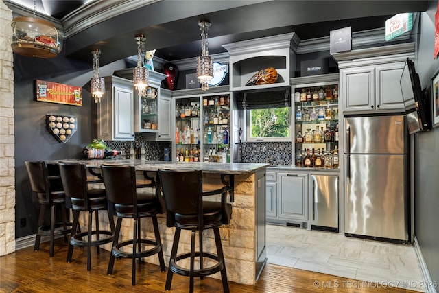 5879 N Eagle Summit Rd, Owasso, OK 74055 - indoor wet bar featuring freestanding refrigerator, crown molding, decorative backsplash, pendant lighting, and light wood-style floors