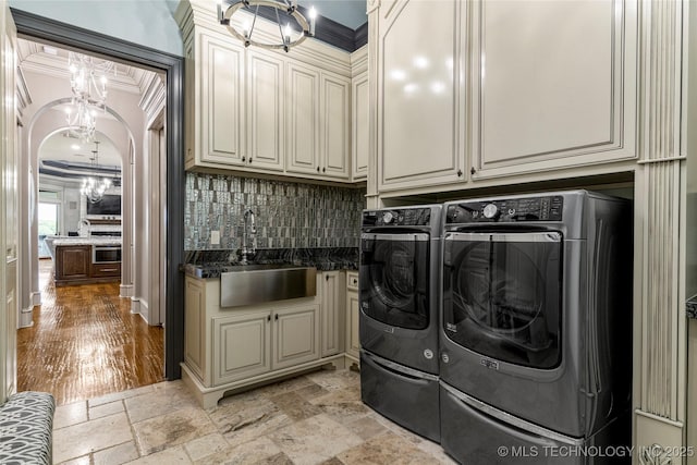 5879 N Eagle Summit Rd, Owasso, OK 74055 - laundry area with washer and clothes dryer, cabinet space, a chandelier, stone tile floors, and ornamental molding
