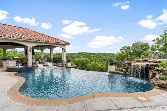 5879 N Eagle Summit Rd, Owasso, OK 74055 - view of swimming pool featuring a gazebo, an outdoor kitchen, a pool with connected hot tub, and a patio
