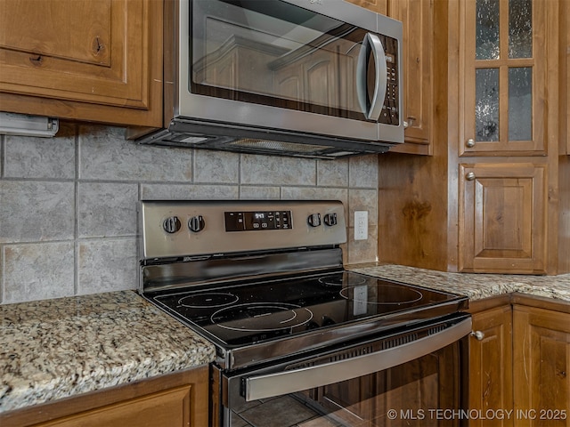 4610 E 142nd St S, Bixby, OK 74008 - kitchen with stainless steel microwave, electric range oven, brown cabinetry, decorative backsplash, and glass insert cabinets