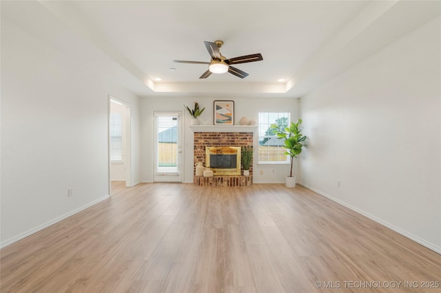 5202 Greenan Dr, Sand Springs, OK 74063 - living room with a tray ceiling, ceiling fan, light wood-type flooring, a brick fireplace, and baseboards