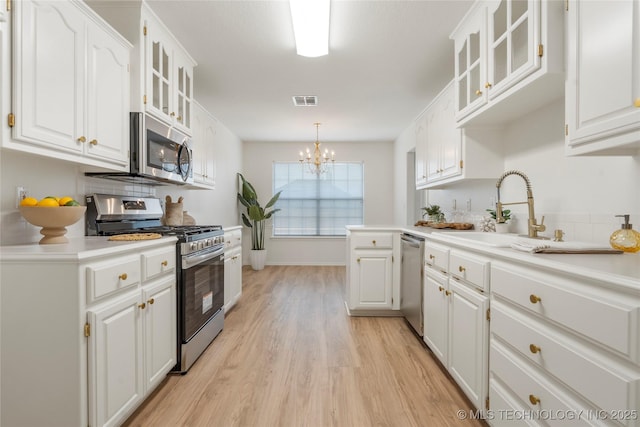 5202 Greenan Dr, Sand Springs, OK 74063 - kitchen featuring stainless steel appliances, a sink, light wood-type flooring, a chandelier, and white cabinets