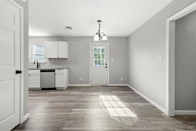 821 N 71st E Ave, Tulsa, OK 74115 - kitchen with dishwasher, white cabinetry, baseboards, light wood finished floors, and pendant lighting