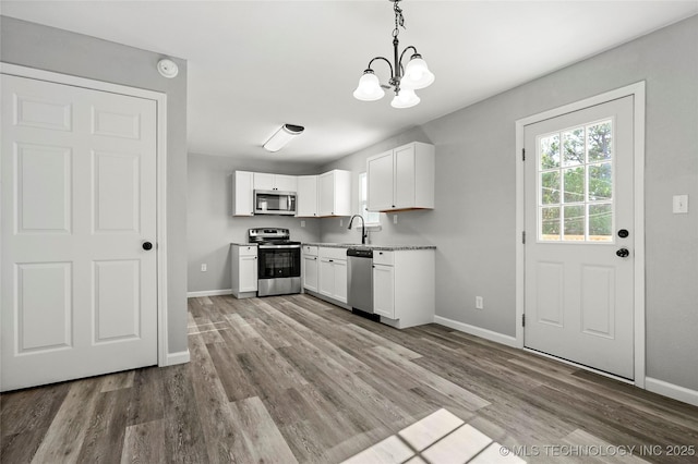 821 N 71st E Ave, Tulsa, OK 74115 - kitchen featuring stainless steel appliances, a chandelier, baseboards, white cabinets, and wood finished floors
