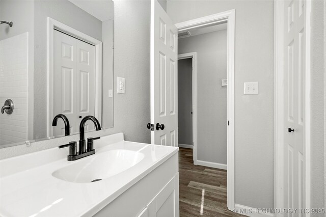 821 N 71st E Ave, Tulsa, OK 74115 - full bathroom featuring wood finished floors, vanity, baseboards, and a shower