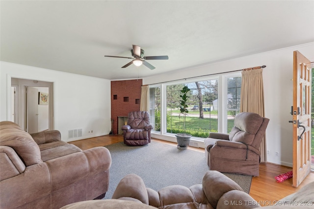 1401 E S Ave, Mcalester, OK 74501 - living room featuring light wood-type flooring, ceiling fan, a fireplace, crown molding, and baseboards