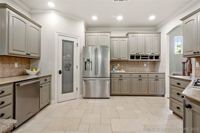 465 E 113th St S, Jenks, OK 74037 - kitchen with stainless steel appliances, ornamental molding, decorative backsplash, light stone counters, and arched walkways