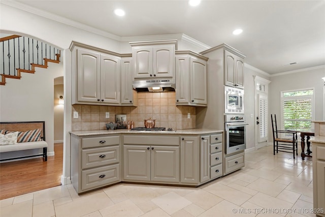 465 E 113th St S, Jenks, OK 74037 - kitchen with stainless steel appliances, arched walkways, under cabinet range hood, backsplash, and baseboards