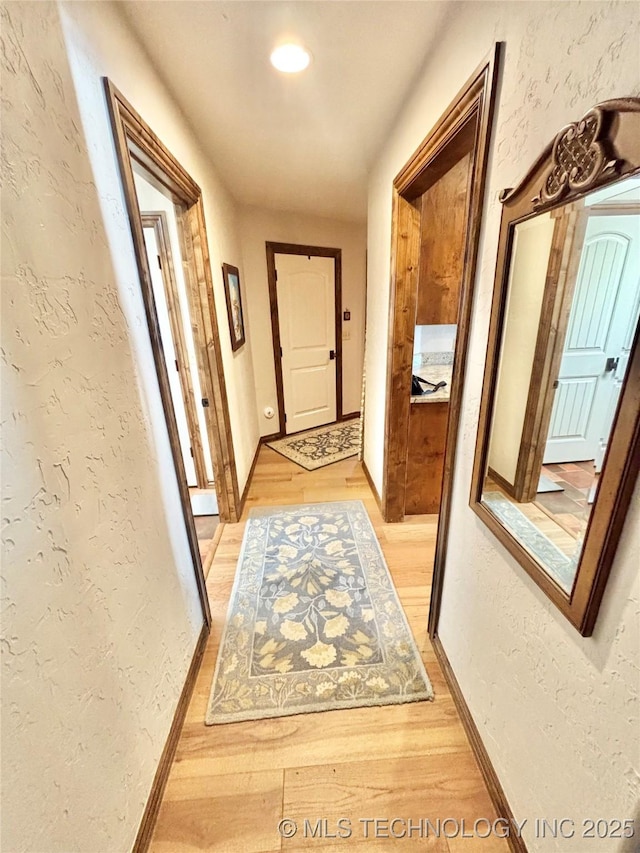 2102 N Peaceful Ln, Stigler, OK 74462 - hallway with a textured wall, light wood-style flooring, and baseboards