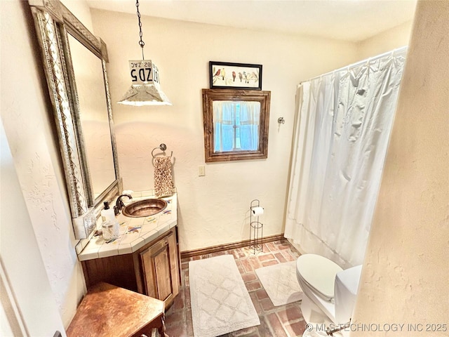 2102 N Peaceful Ln, Stigler, OK 74462 - full bathroom with toilet, vanity, baseboards, brick patterned flooring, and a shower with curtain