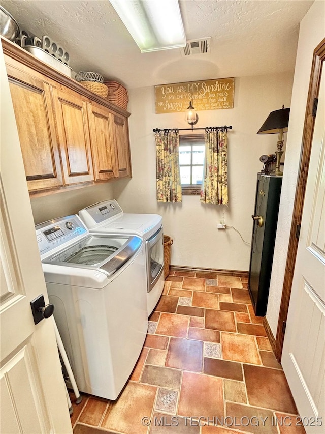 2102 N Peaceful Ln, Stigler, OK 74462 - laundry area with washer and clothes dryer, cabinet space, a textured ceiling, light stone finish flooring, and baseboards