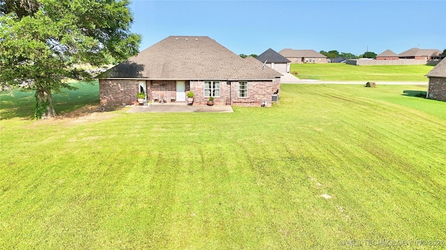 2102 N Peaceful Ln, Stigler, OK 74462 - back of house with a patio area, a lawn, brick siding, and a shingled roof