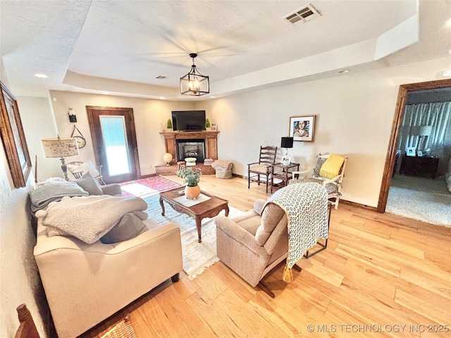 2102 N Peaceful Ln, Stigler, OK 74462 - living room with a tray ceiling, light wood-style floors, a fireplace with raised hearth, baseboards, and recessed lighting