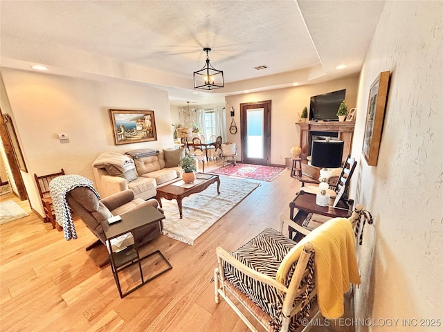 2102 N Peaceful Ln, Stigler, OK 74462 - living room featuring a chandelier, light wood-style flooring, a textured wall, a tray ceiling, and recessed lighting