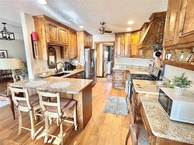 2102 N Peaceful Ln, Stigler, OK 74462 - kitchen featuring stainless steel appliances, a peninsula, a sink, brown cabinetry, and recessed lighting