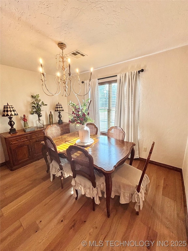 2102 N Peaceful Ln, Stigler, OK 74462 - dining space featuring light wood-style flooring, a textured ceiling, a chandelier, and baseboards