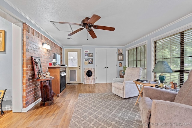 1307 Chickasaw Rd, Calera, OK 74730 - living room featuring crown molding, healthy amount of natural light, light wood-style floors, a ceiling fan, and a fireplace