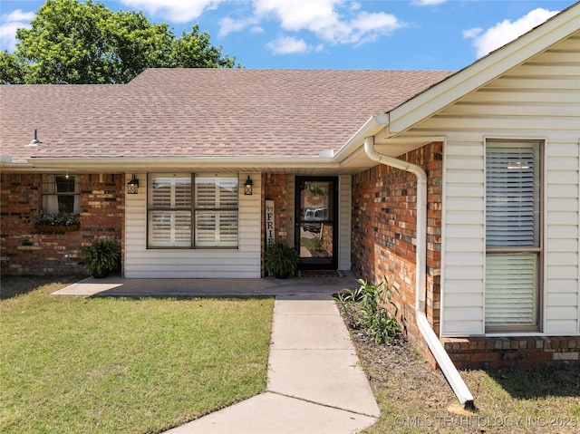 2003 8th NW, Ardmore, OK 73401 - doorway to property with brick siding, roof with shingles, and a lawn