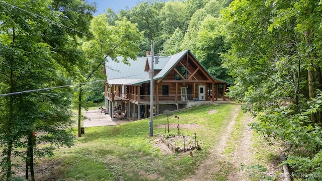 21745 E 660th Rd, Tahlequah, OK 74464 - back of house featuring a lawn, driveway, metal roof, a wooded view, and a chimney