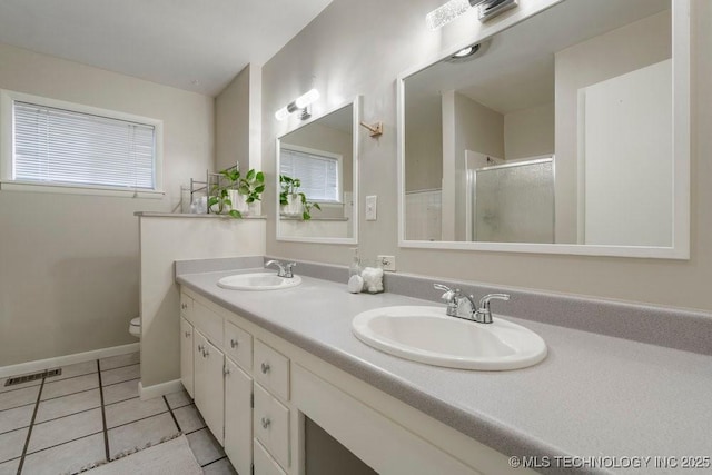 953 E 37th St, Tulsa, OK 74105 - bathroom featuring double vanity, a stall shower, tile patterned floors, toilet, and baseboards