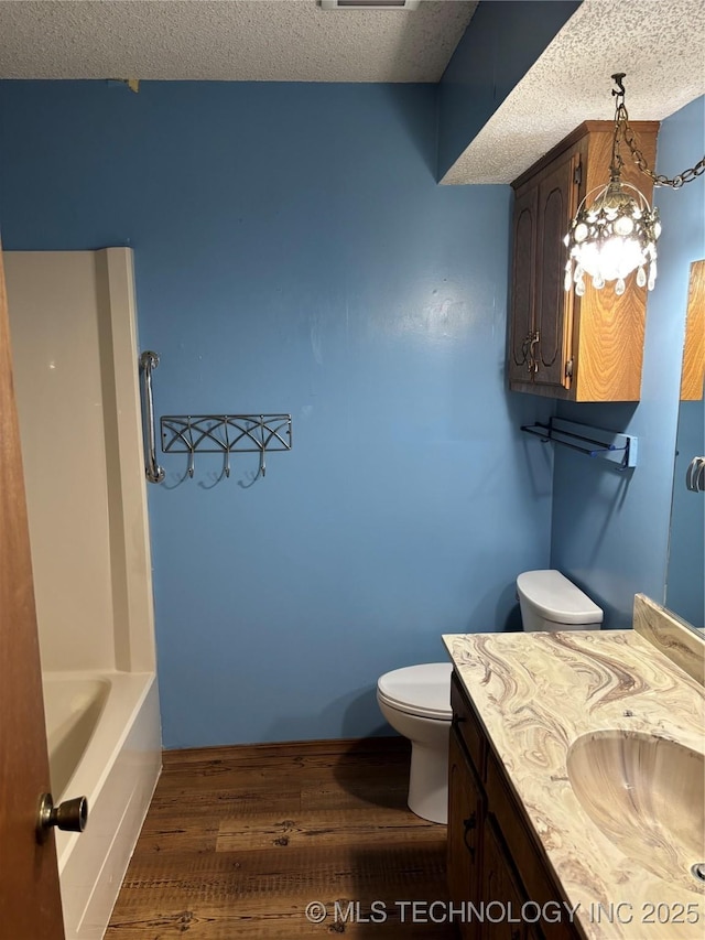 1339 E 9th St, Cushing, OK 74023 - bathroom with toilet, wood finished floors, vanity, and a textured ceiling