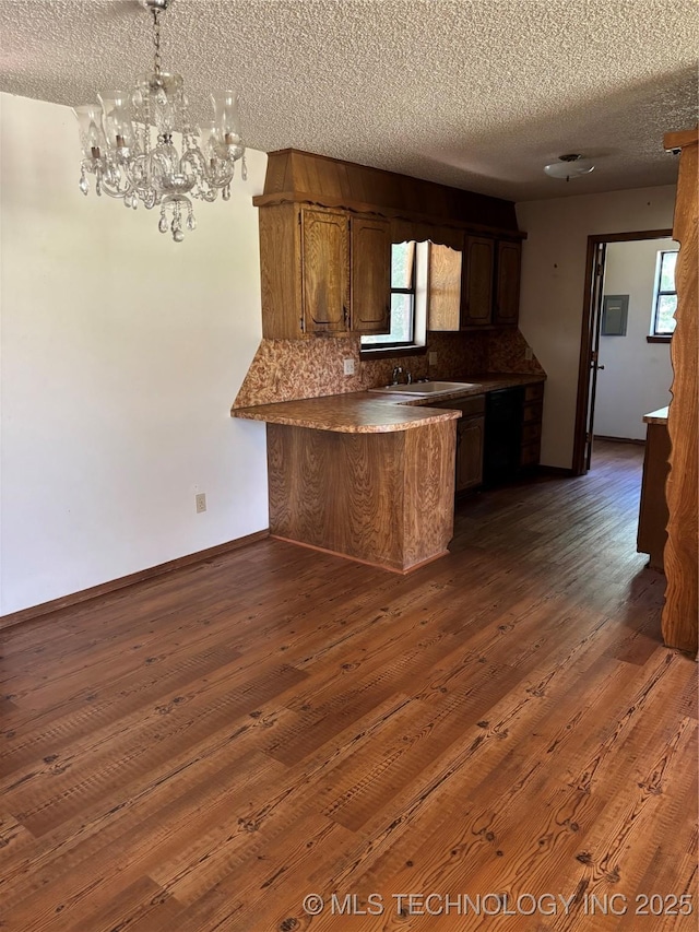 1339 E 9th St, Cushing, OK 74023 - kitchen featuring a peninsula, a textured ceiling, a chandelier, dark wood-style floors, and a sink