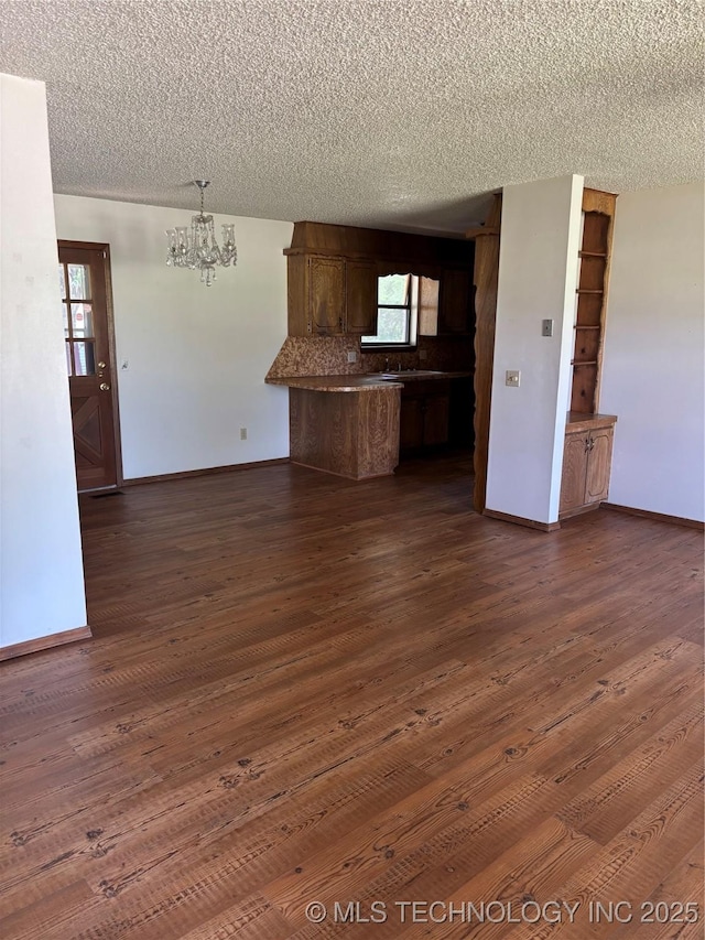 1339 E 9th St, Cushing, OK 74023 - kitchen with a chandelier, a textured ceiling, a peninsula, dark wood-style floors, and baseboards