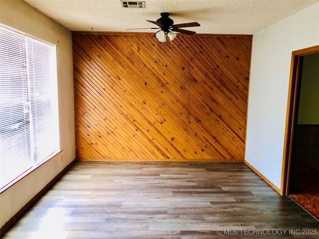 3814 E Dripping Springs Rd, Cushing, OK 74023 - unfurnished room featuring a ceiling fan, wooden walls, baseboards, wood finished floors, and a textured ceiling