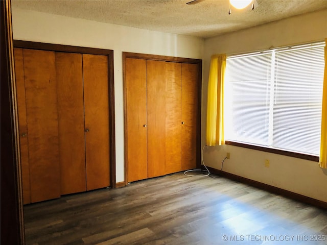 3814 E Dripping Springs Rd, Cushing, OK 74023 - unfurnished bedroom with multiple closets, wood finished floors, a textured ceiling, and baseboards