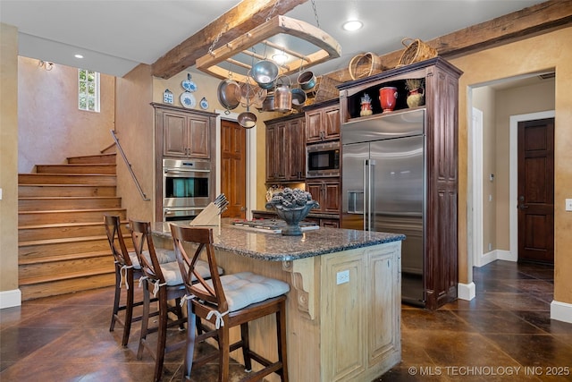 10144 N Dover Pl, Owasso, OK 74055 - kitchen with built in appliances, beam ceiling, dark stone countertops, a breakfast bar area, and a center island