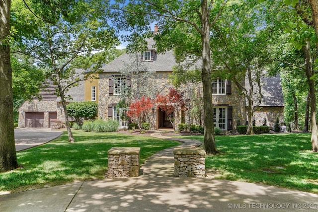 10144 N Dover Pl, Owasso, OK 74055 - english style home with stone siding, a garage, a front yard, and concrete driveway
